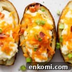 Twice-Baked Potatoes with Cheddar and Crispy Bacon 9 Three twice baked potatoes on a plate topped with cheese, bacon and green onions.