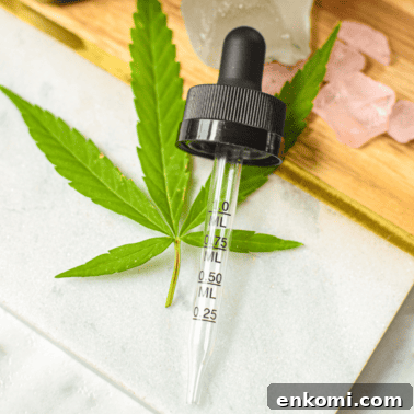 A picture of a cannabis tincture and a hand pulling out the dropper.