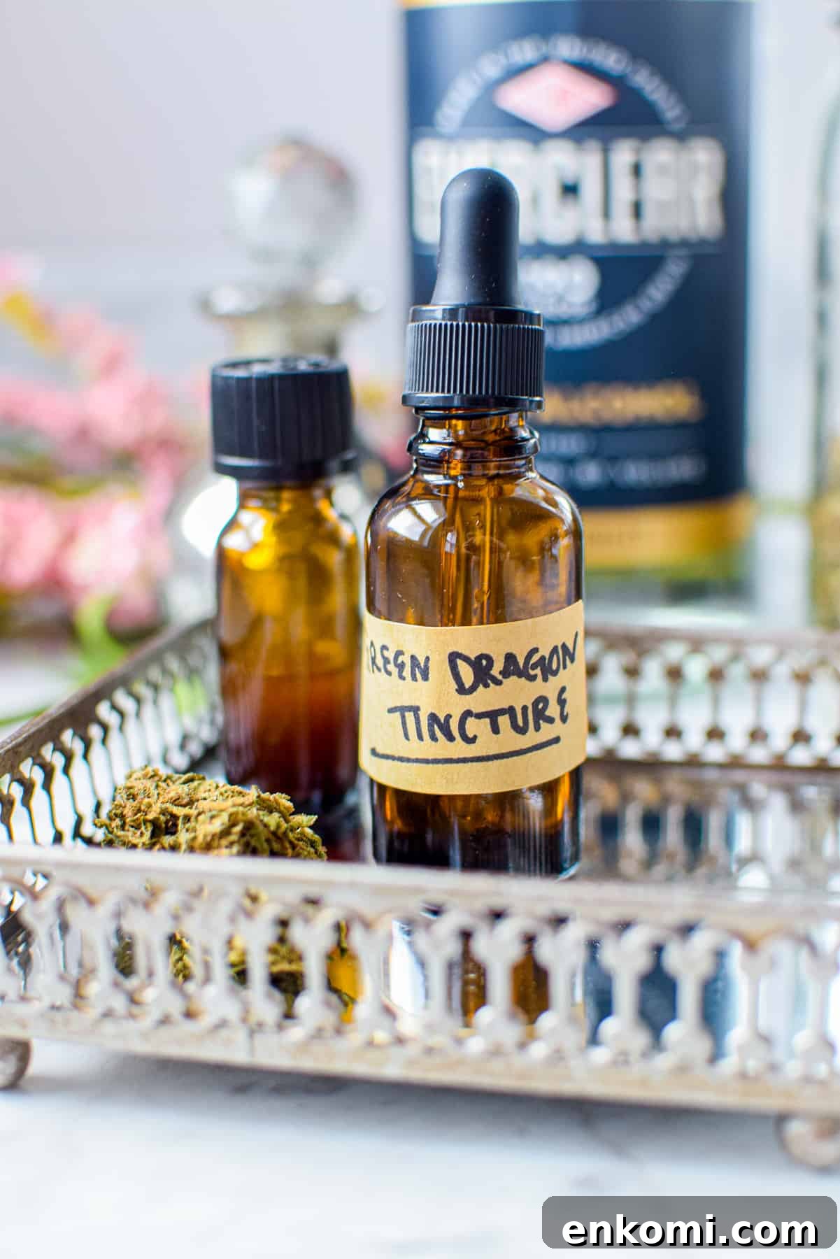 A white countertop with a metal tray with a amber tincture bottle labeled green dragon tincture with cannabis to the lefthand side, ever clear bottle in the background