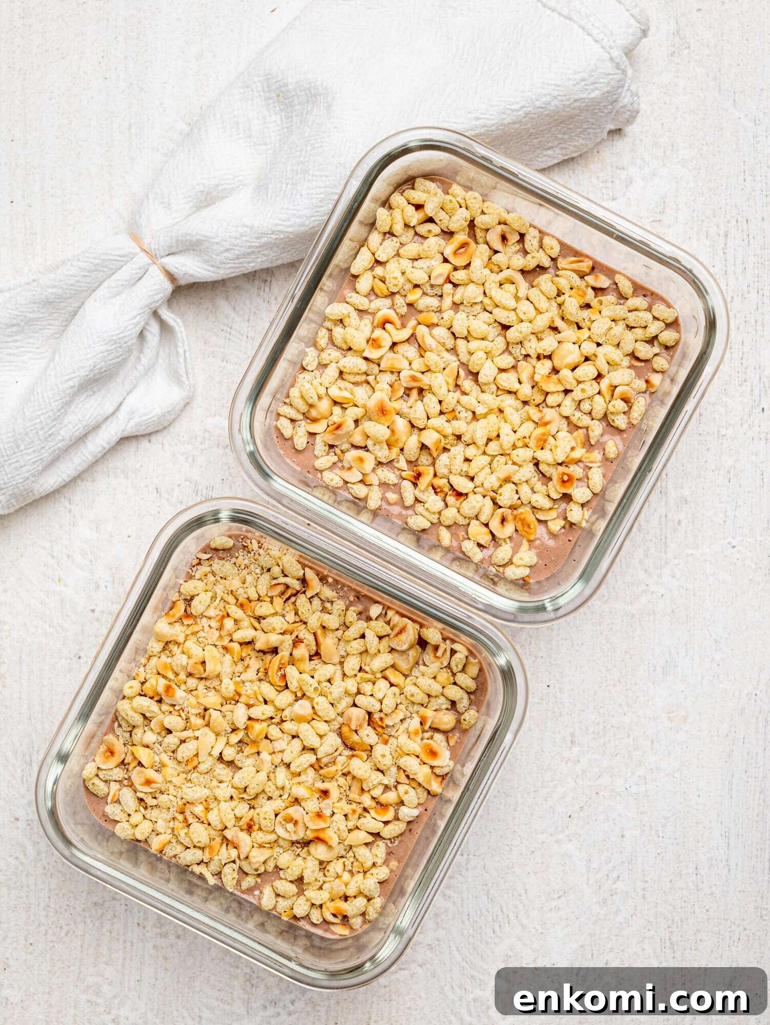 Creamy chocolate protein overnight oats topped with puffed rice and hazelnuts in meal-prep containers.
