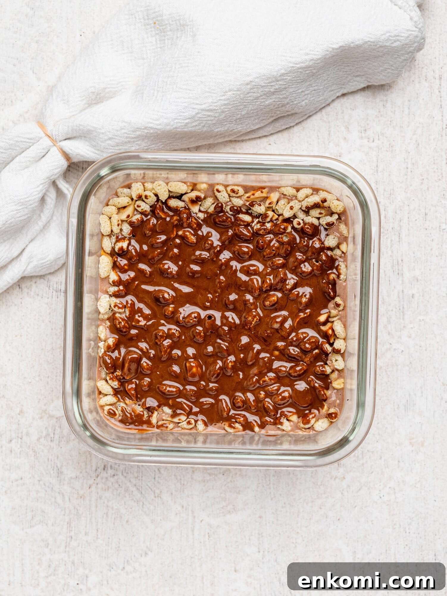 Creamy chocolate protein overnight oats topped with puffed rice and hazelnuts, and dark chocolate.