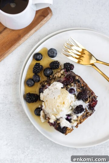 Overhead view of a piece of baked berry oatmeal with coconut whipped cream and syrup on top