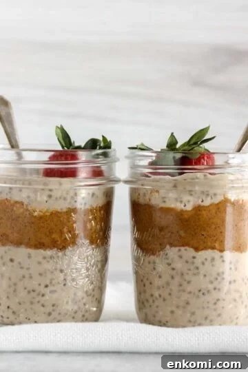 Two mason jars filled with overnight oats and almond butter topped with a strawberry.