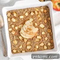 Warm Apple Cinnamon Baked Oatmeal with Crunchy Topping 14 Baked apple oatmeal topped with apple slices in a square white baking dish with apples and syrup on the side.