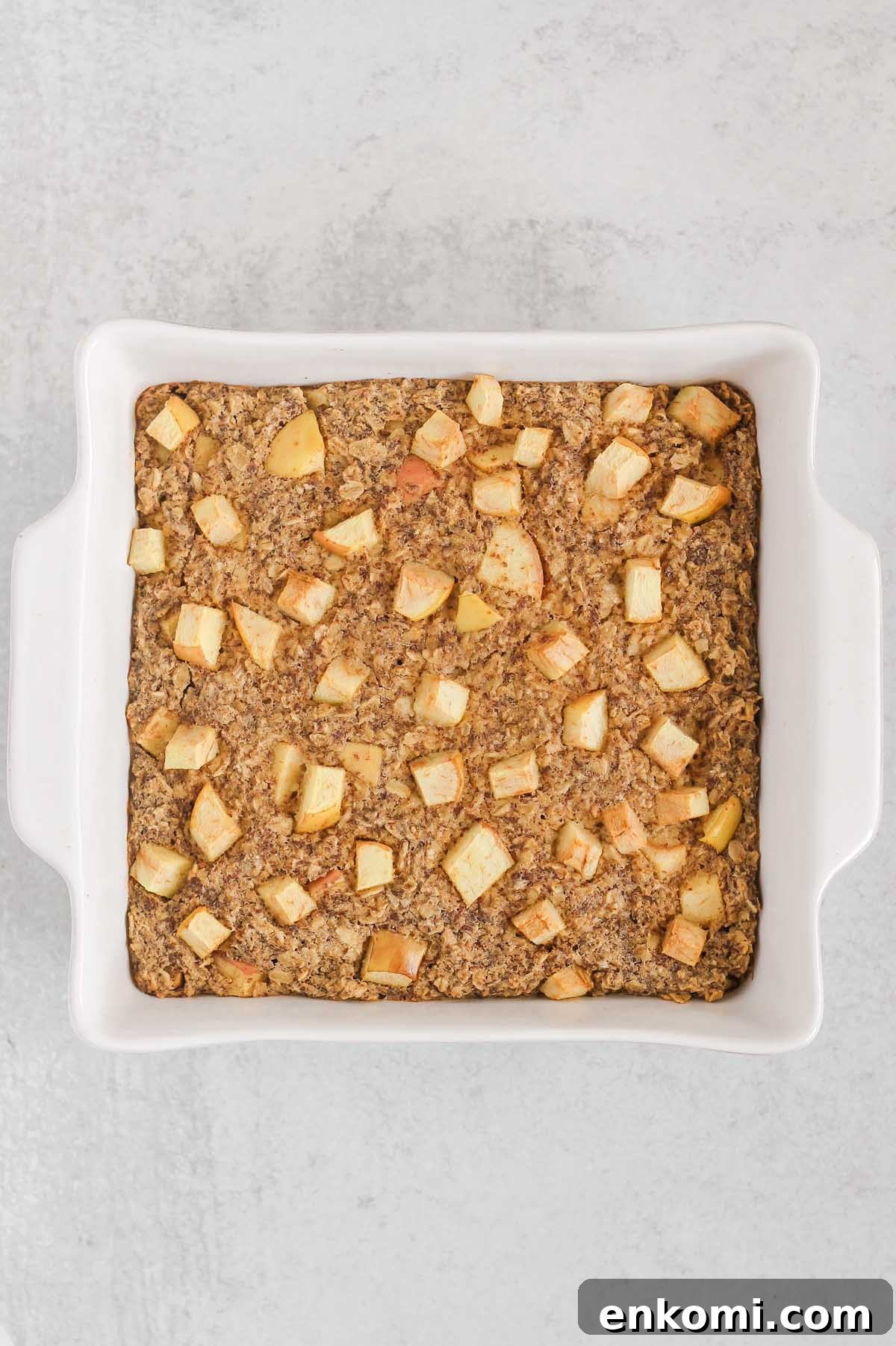 Warm Apple Cinnamon Baked Oatmeal with Crunchy Topping 7 Baked apple cinnamon oatmeal in a square white baking dish.