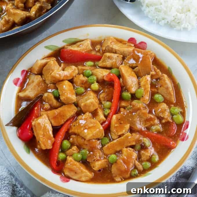 Pork Guisantes in a serving bowl with plate of steamed rice on the side