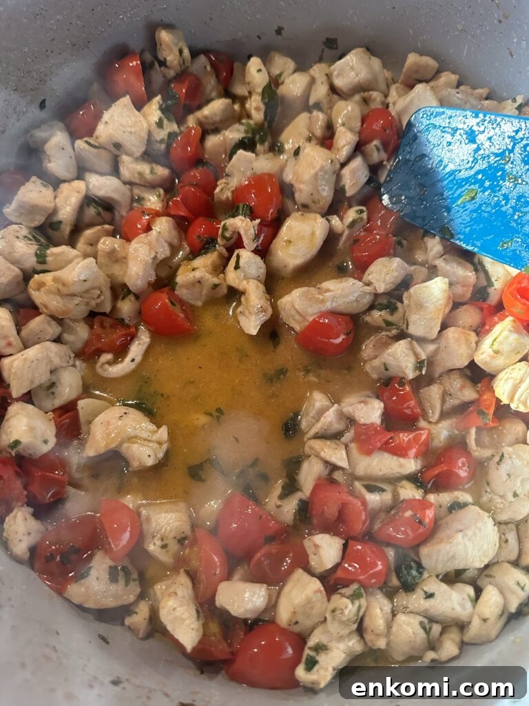 Pieces of chicken cooking in a pot with cherry tomatoes