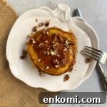 Pumpkin pancakes piled on a pumpkin shaped plate sitting on top of a piece of burlap.