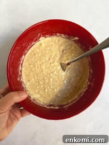 Mixed pancake batter in a red bowl with a fork.