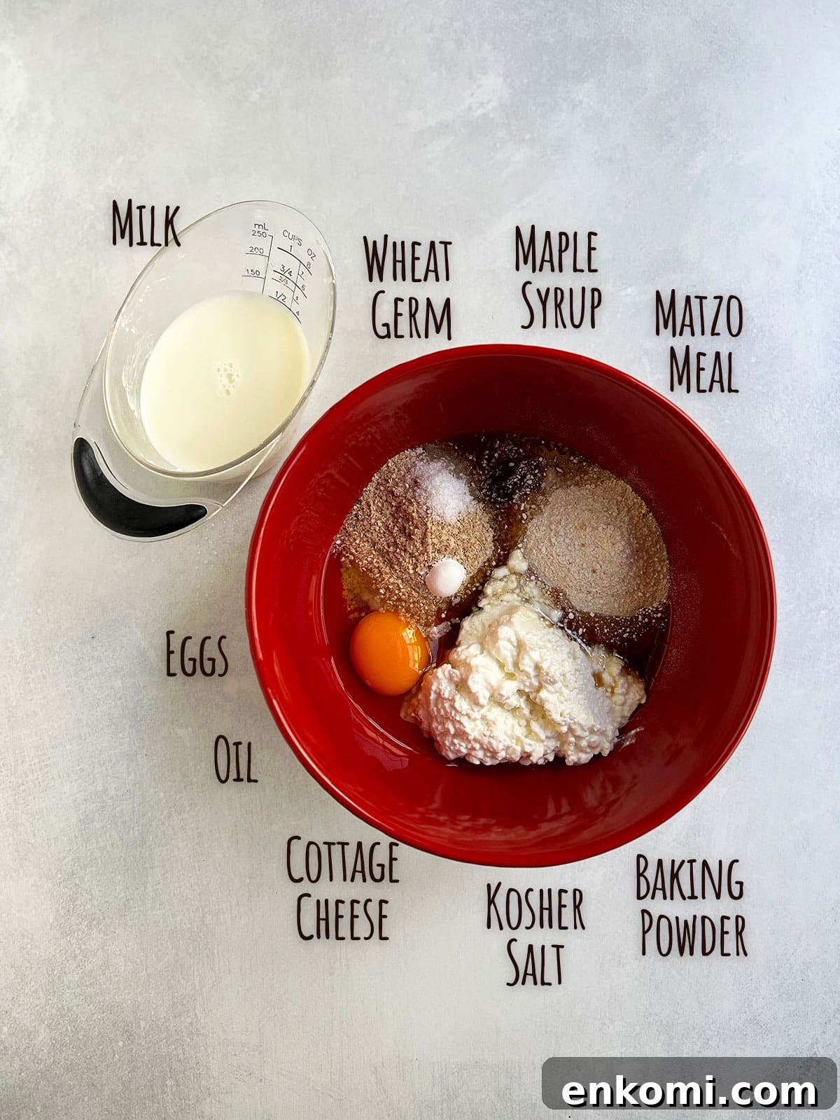 Ingredient shot with all pancake ingredients in a red bowl except for the milk which is in a measuring cup.