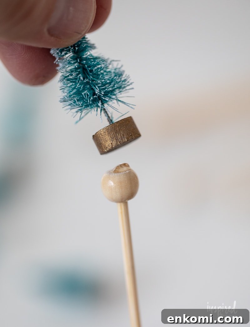 hand glueing a small bottle brush trees to a wood stick.