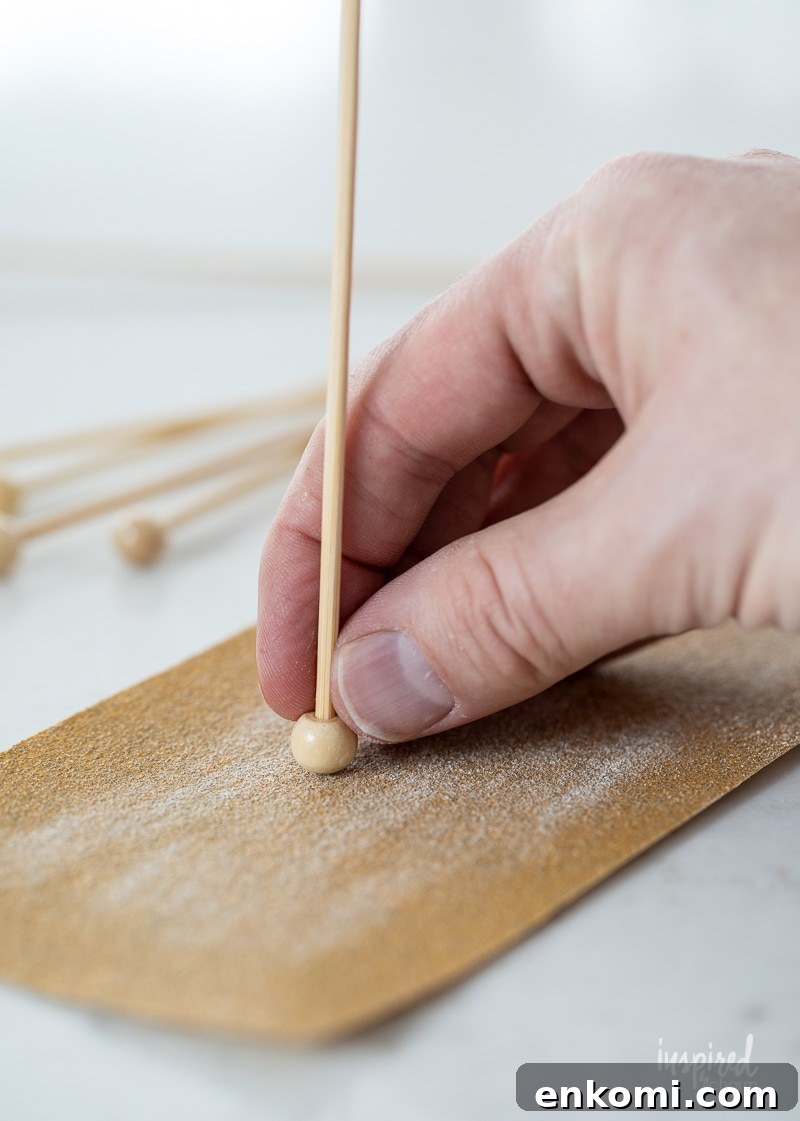 hand sanding the ball on a wood stick.