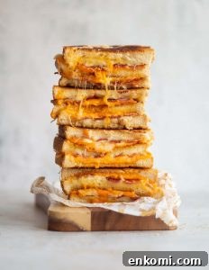 4 sandwich halves stacked on each other showing filling on small wooden board