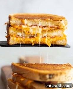 half of grilled cheese resting on black spatula with cheese dripping out
