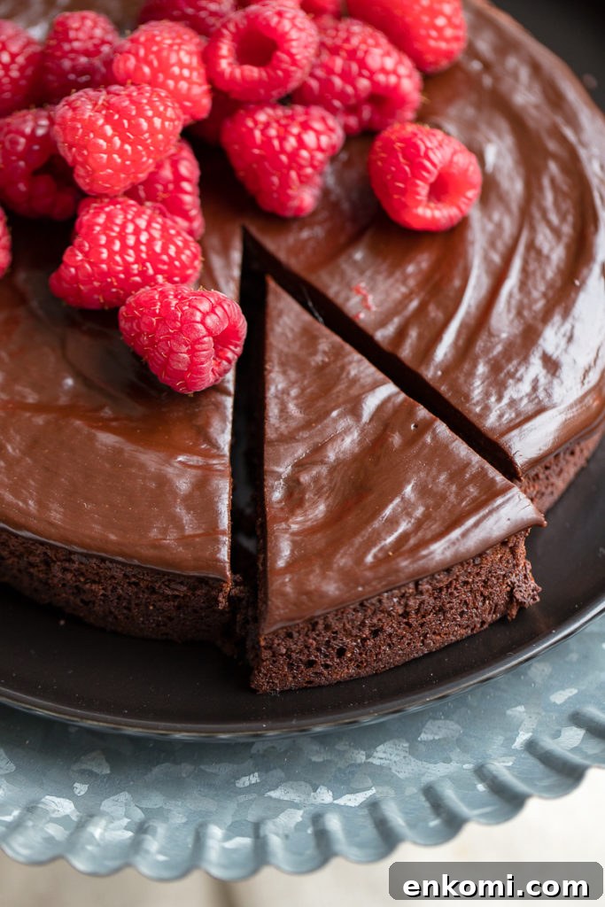 Decadent Flourless Chocolate Cake Recipe 5 A just-cut slice of rich, perfect flourless chocolate cake with chocolate ganache and fresh raspberries.