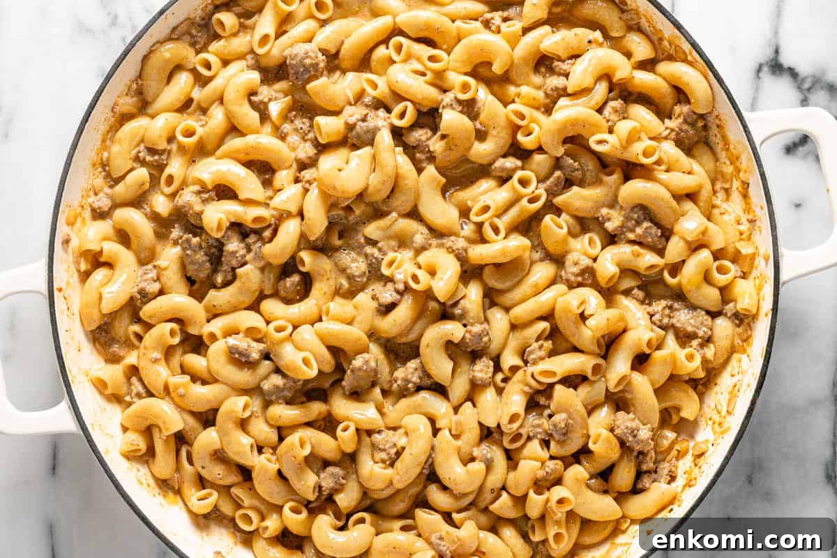 Large pan filled with cooked noodles and ground beef in sauce.