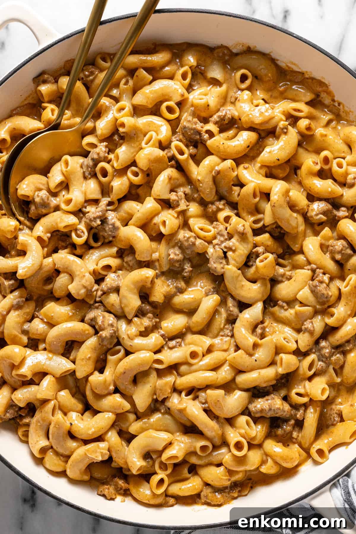 Large pan filled with homemade hamburger helper and 2 serving spoons.