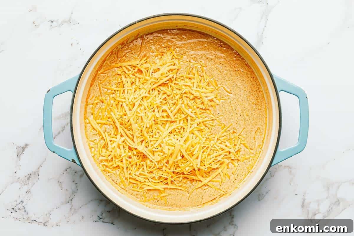 One-Pot Creamy Buffalo Chicken Pasta 5 Shredded cheese in a pan of creamy buffalo sauce.