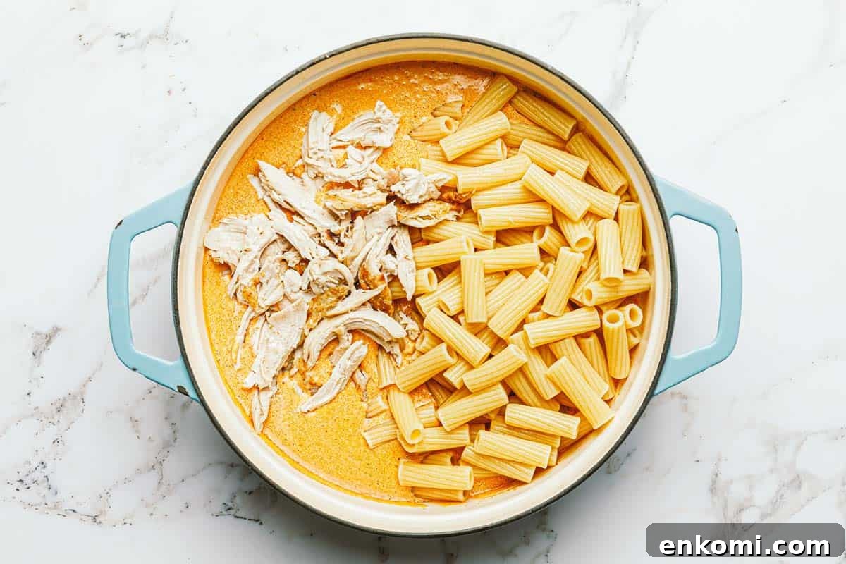 One-Pot Creamy Buffalo Chicken Pasta 6 Pasta and shredded chicken added to a pan of creamy buffalo sauce.