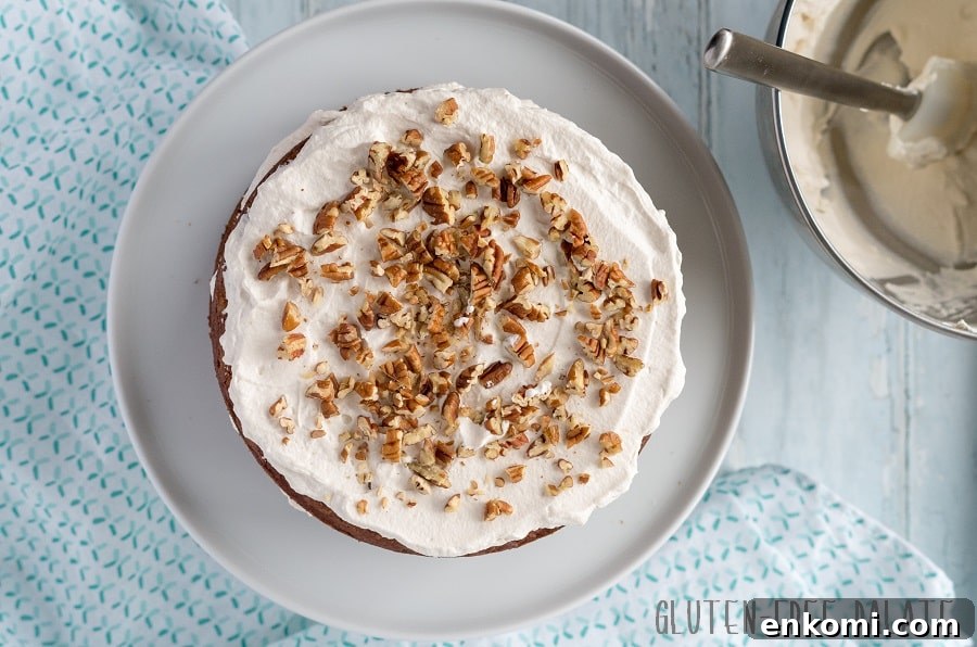 Gluten-Free Hummingbird Cake Recipe with Cream Cheese Frosting 6 top down view of a grain-free hummingbird cake with white frosting and chopped pecans on top