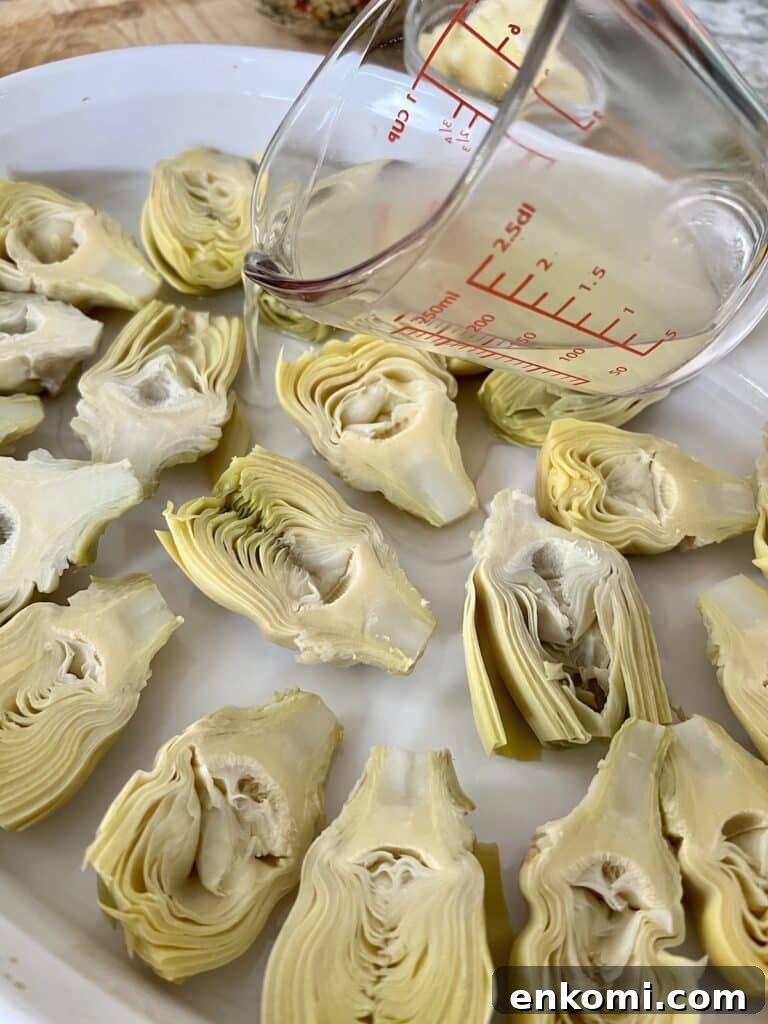 Oven-Roasted Italian Artichoke Hearts with Lemon Breadcrumbs 12 Pouring lemon and white wine into baking dish with artichoke halves.
