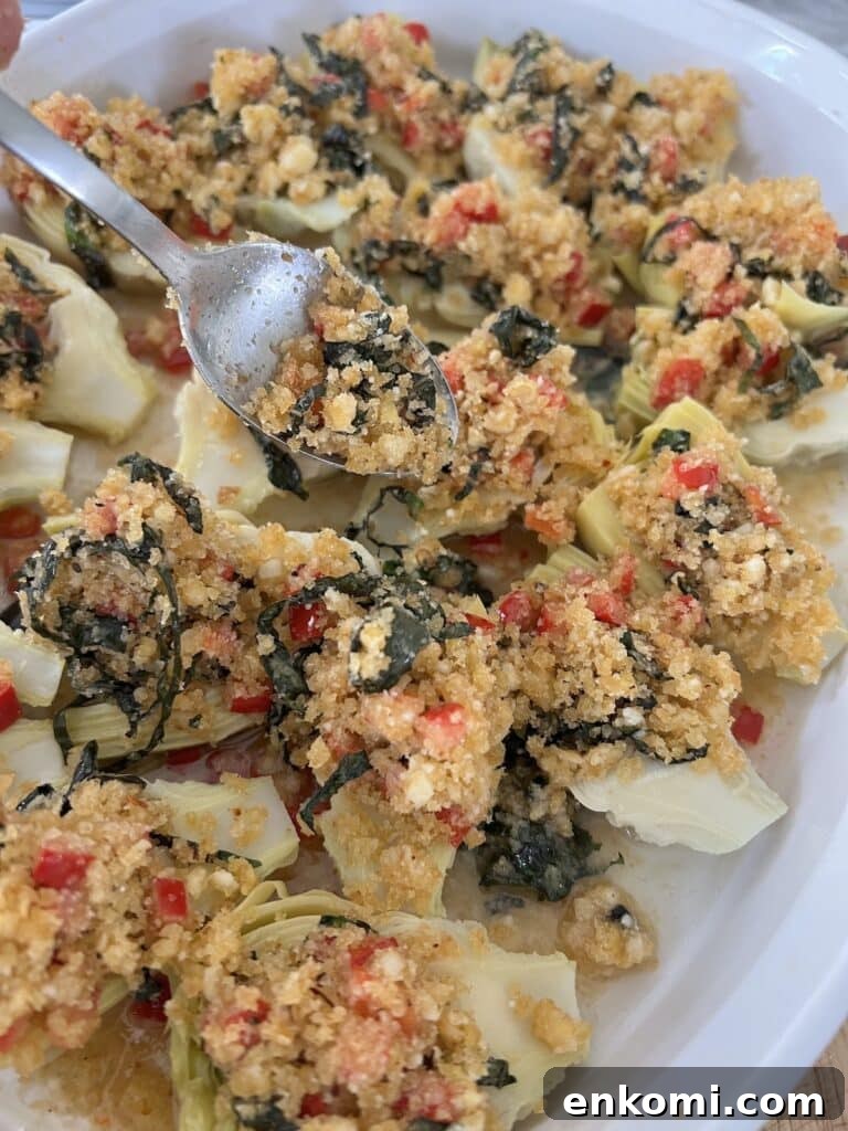 Oven-Roasted Italian Artichoke Hearts with Lemon Breadcrumbs 13 Spooning lemon breadcrumbs onto halves in the baking dish.