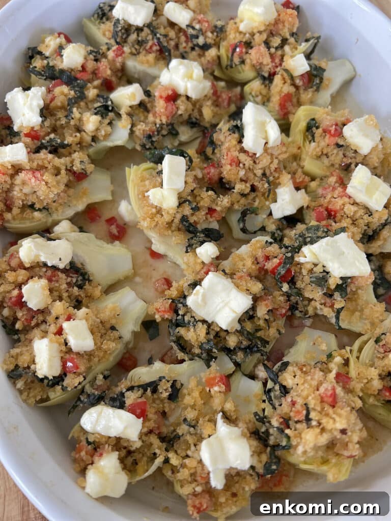 Oven-Roasted Italian Artichoke Hearts with Lemon Breadcrumbs 14 Breadrumb topped artichoke heart halves topped with small cubes of butter in white baking dish.