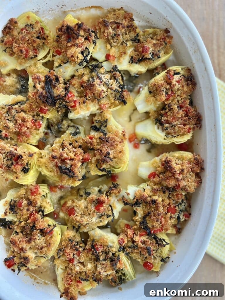 Oven-Roasted Italian Artichoke Hearts with Lemon Breadcrumbs 17 Finished, baked italian artichoke hearts oreganata in white baking dish on yellow towel.