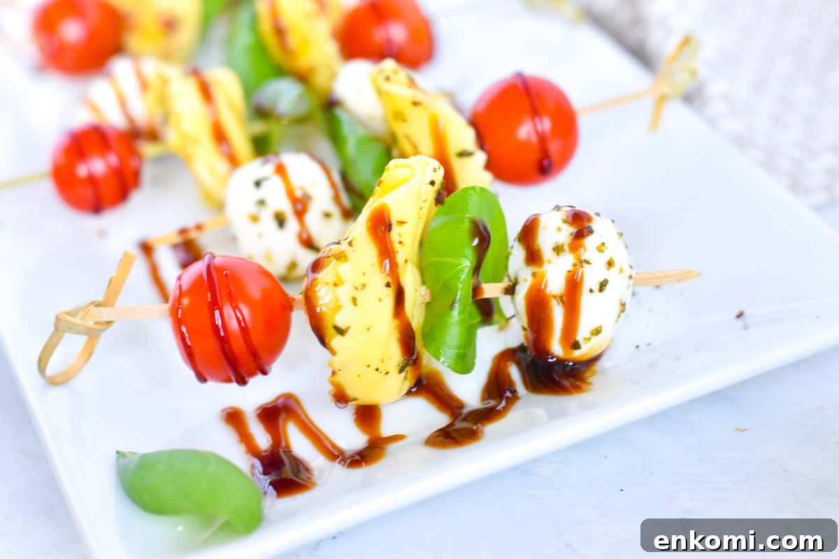 Caprese Tortellini Skewers with Cherry Tomatoes and Basil 6 Caprese skewers on a white platter