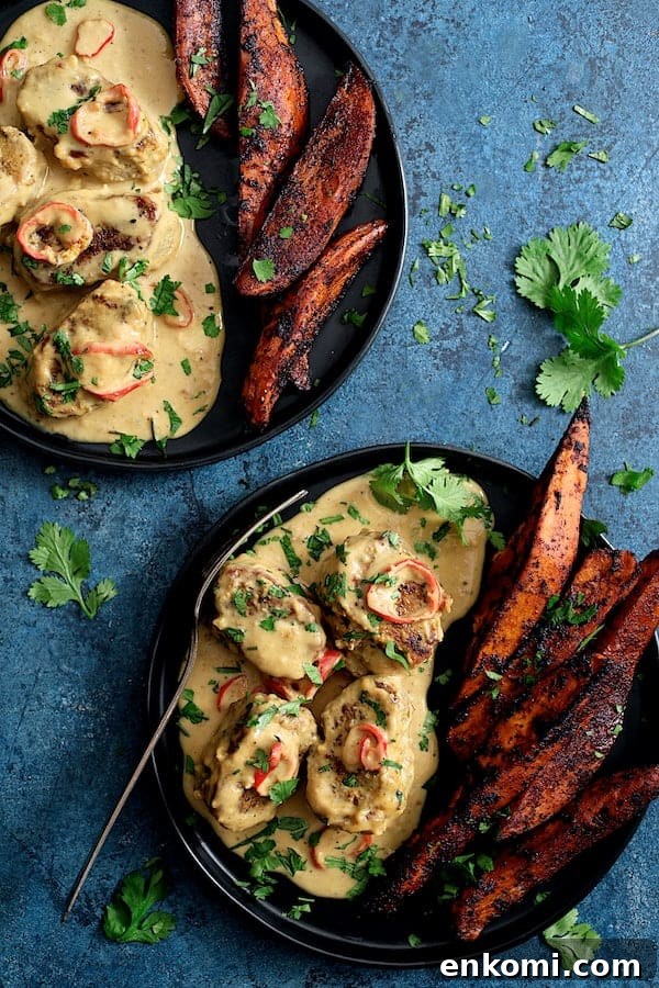 Spicy Tahini Pork Medallions with Harissa Sweet Potato Wedges 12 Photo of two servings of Spicy Tahini Pork Medallions with Harissa Roasted Sweet Potato Wedges on blue background garnished with cilantro.