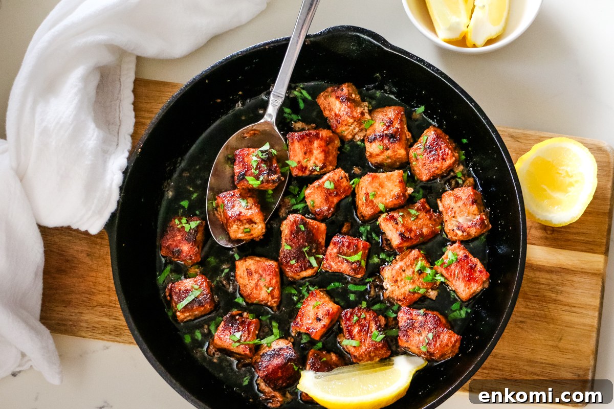 pork bites in cast iron skillet with spoon.