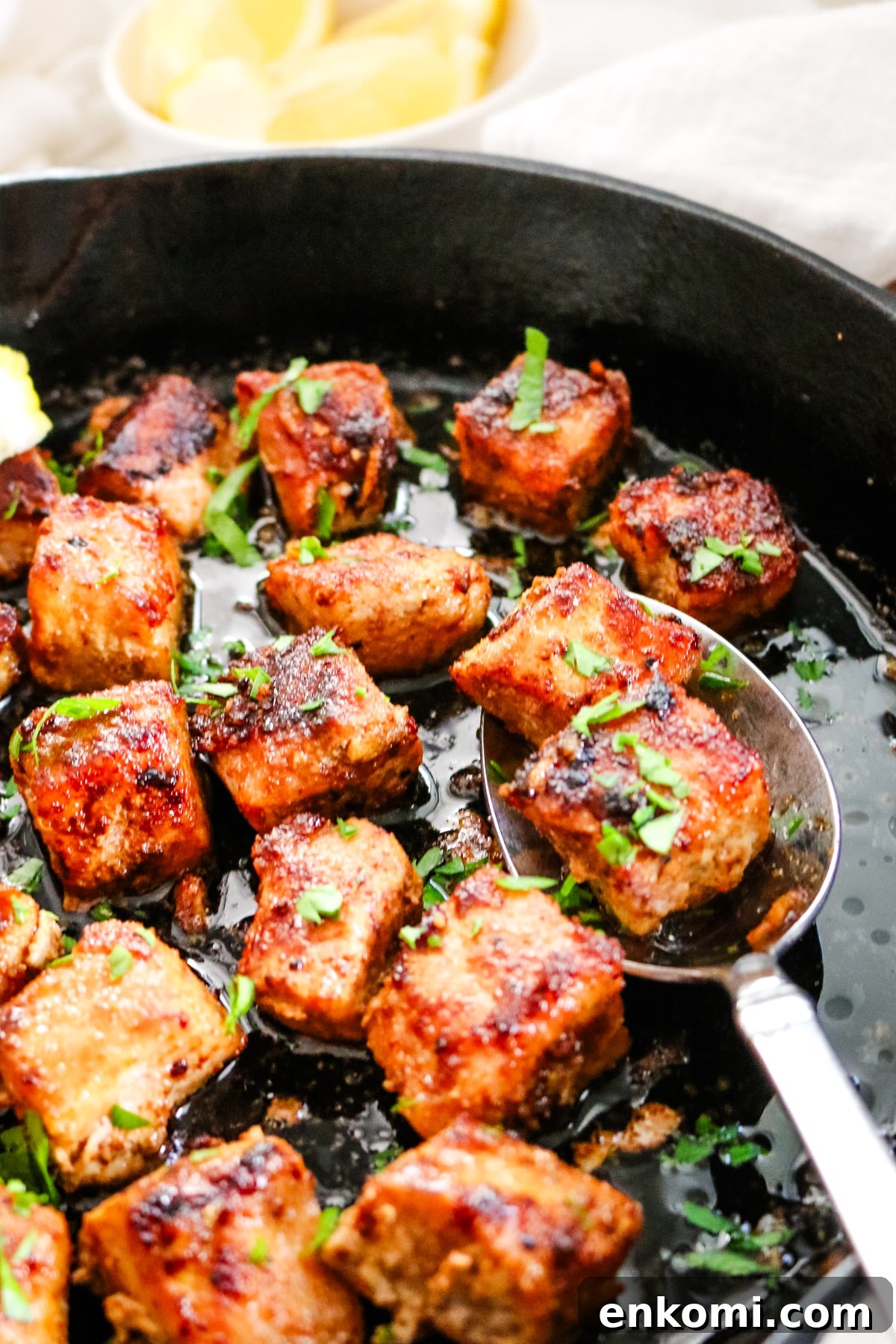 pork bites in cast iron skillet with a metal spoon.
