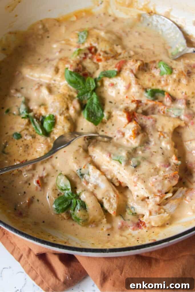 20-Minute Marry Me Chicken with Creamy Sun-Dried Tomato Sauce 11 Close up of sliced chicken breast in creamy sundried tomato sauce in a large white skillet.