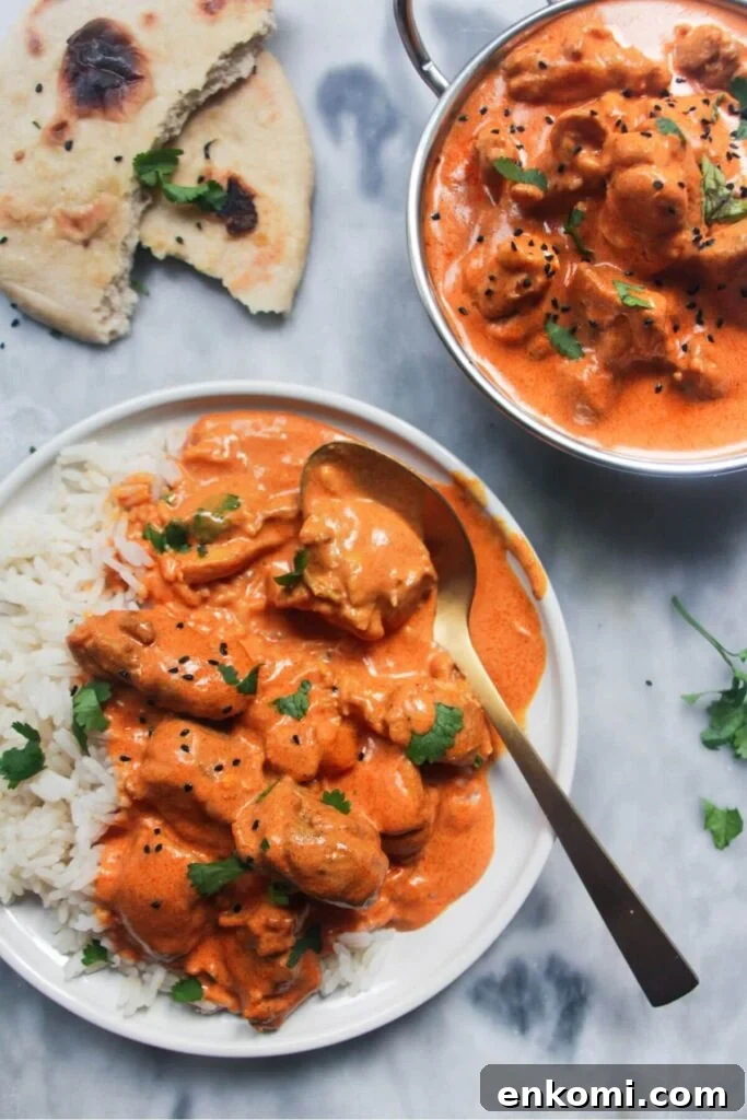 20-Minute Marry Me Chicken with Creamy Sun-Dried Tomato Sauce 14 White plate with rice and butter chicken with bowl of butter chicken in the background and garlic naan.