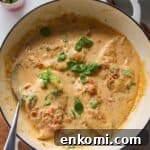 Chicken breasts in creamy sundried tomato sauce in a large white skillet.