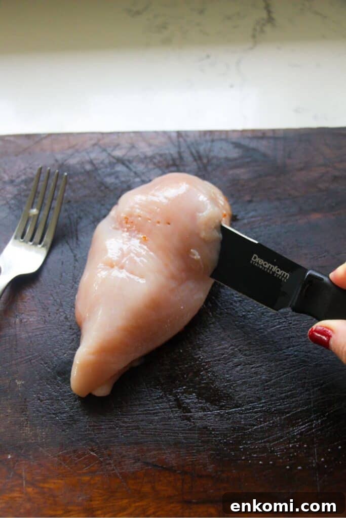 20-Minute Marry Me Chicken with Creamy Sun-Dried Tomato Sauce 4 Small knife cutting a chicken breast in half on a wooden board.