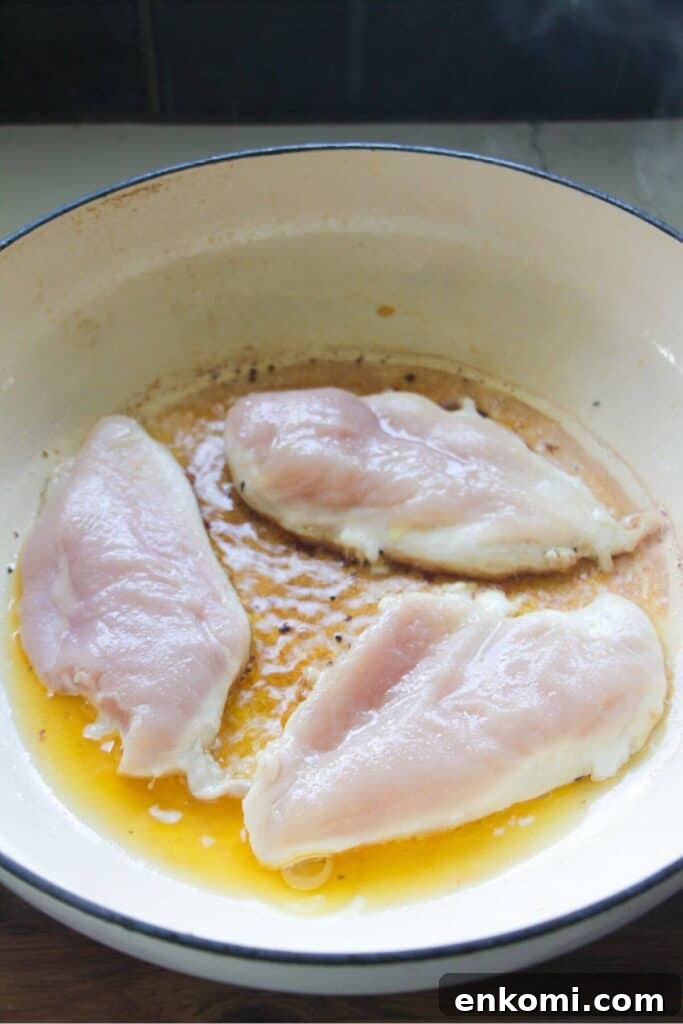20-Minute Marry Me Chicken with Creamy Sun-Dried Tomato Sauce 5 Three chicken breasts cooking in a large white skillet.