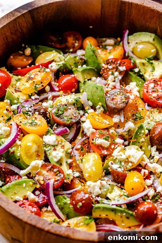 Creamy Avocado and Tomato Salad with Lime Vinaigrette 4 side shot of wooden salad bowl filled with tomatoes, onions, avocado, and bleu cheese
