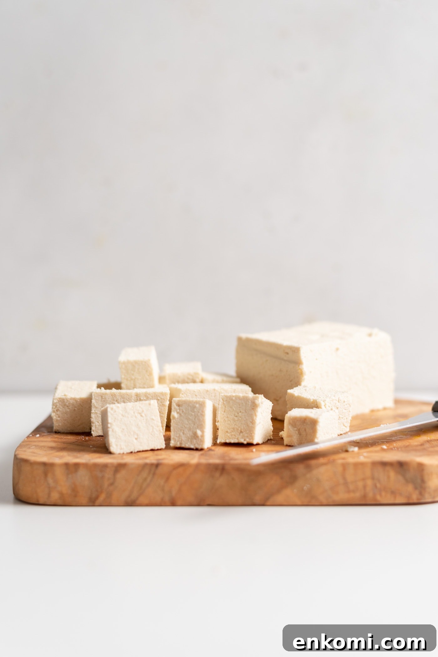 How to Press Tofu for Crispy, Firm Results 2 Cubed tofu on a cutting board with a knife