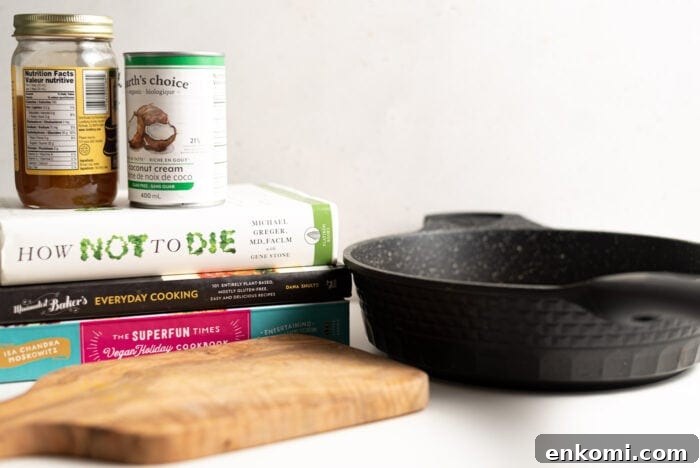 How to Press Tofu for Crispy, Firm Results 3 Cutting board, black frying pan and a stack of books with 2 cans of food top of them.