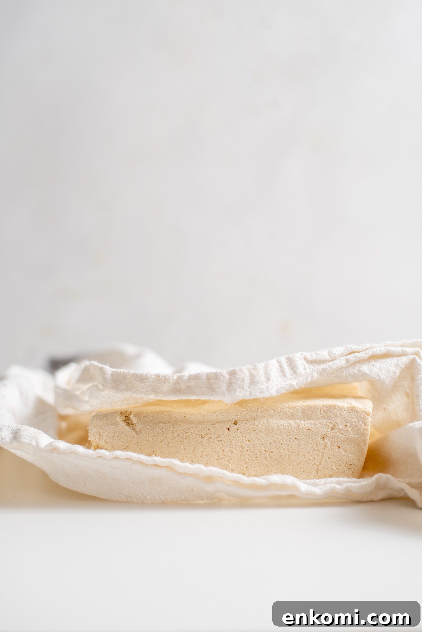 How to Press Tofu for Crispy, Firm Results 4 A block of tofu wrapped in a white dish cloth.