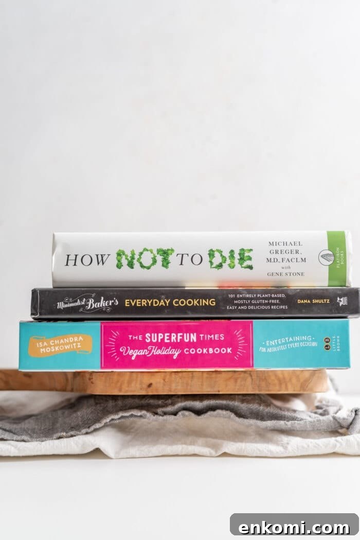 How to Press Tofu for Crispy, Firm Results 6 3 vegan books sitting on a block of tofu wrapped in a dish cloth.
