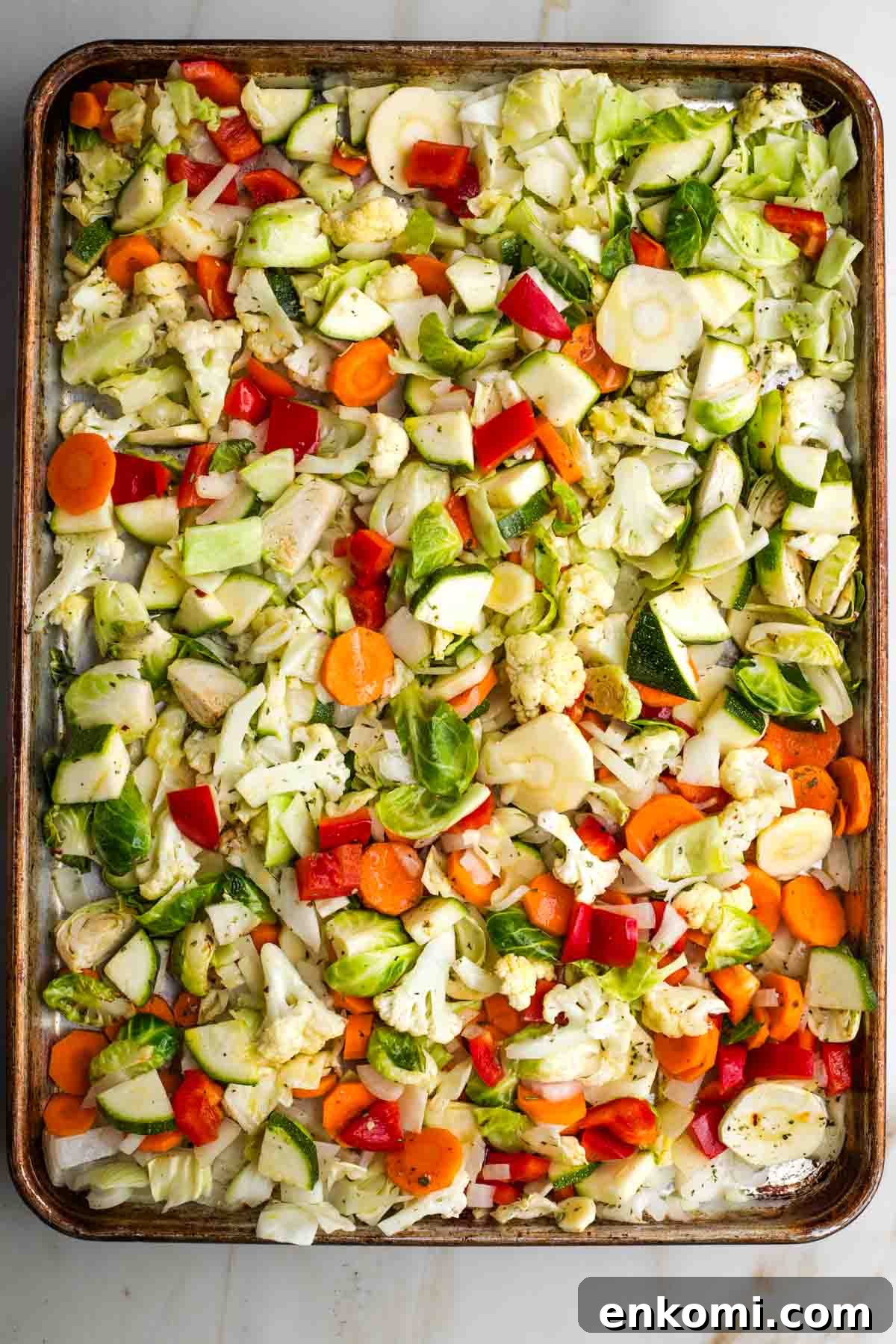 Colorful assortment of chopped veggies on a large rimmed baking sheet.