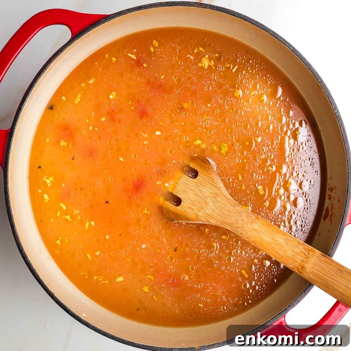 Tomatoes and stock being added to a pot.