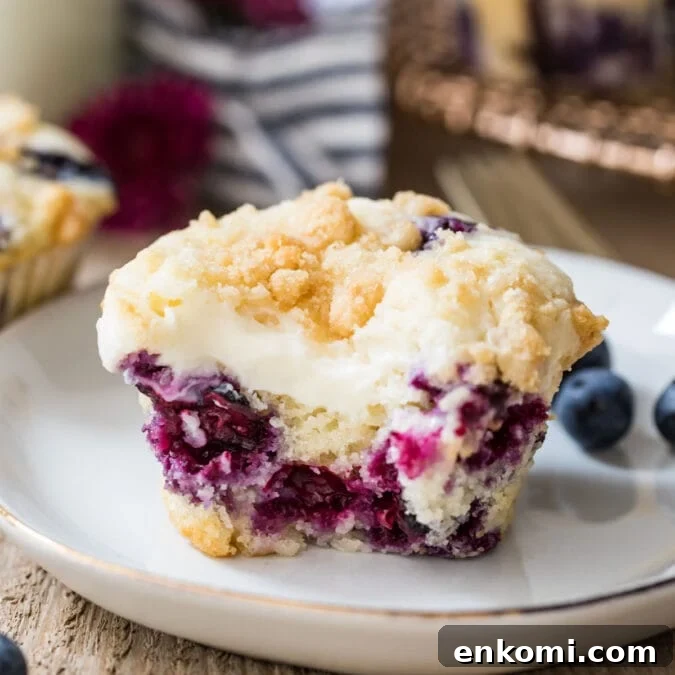 30 Muffin Recipes: Sweet, Savory & Seasonal Ideas 27 Closeup of blueberry cream cheese muffin with a bite taken out of it on a white plate.