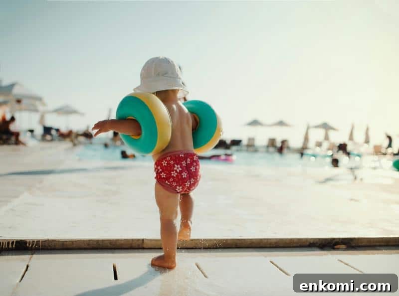 Toddler Travel Clothing Checklist: What to Pack for Trips 4 toddler in swim diaper, bucket hat, and arm floats