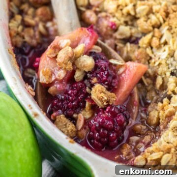 Apple and Blackberry Crumble Recipe for Summer Desserts 15 Wooden spoon dipped in baking dish of apple blackberry crumble.