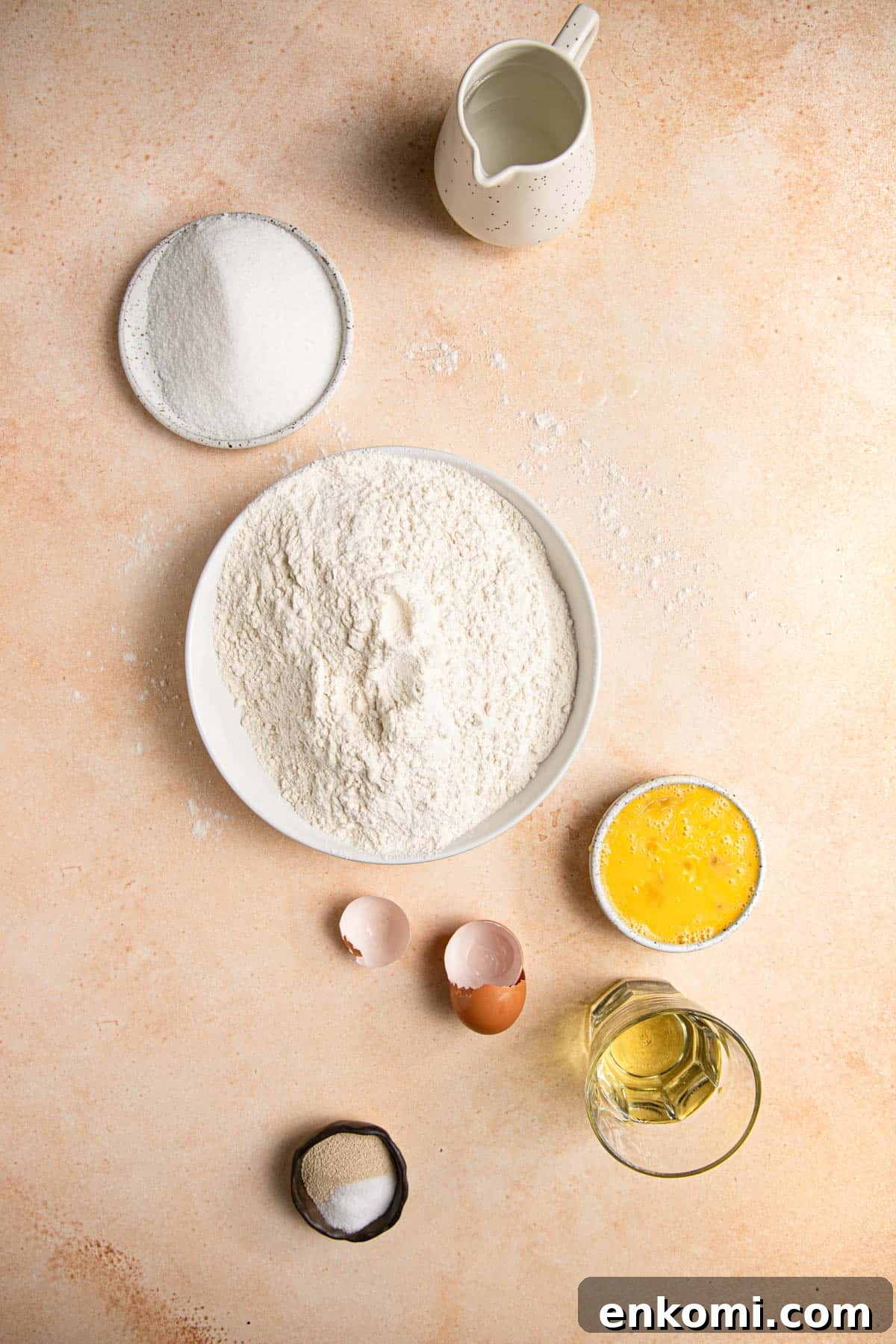 ingredients in bowls water, sugar, flour, oil, eggs, yeast and salt