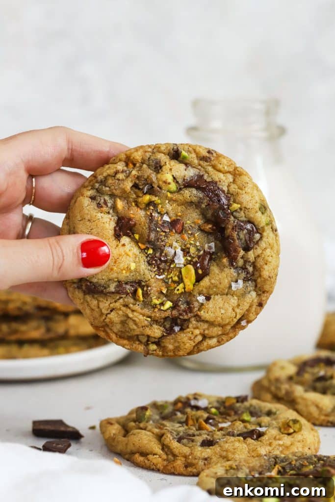 Hand holding a gluten-free brown butter chocolate chunk pistachio cookie
