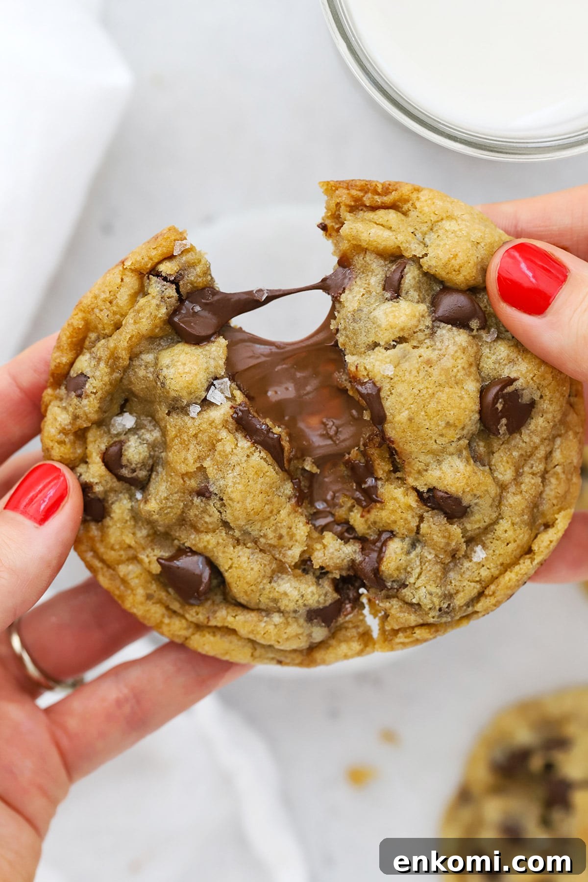 Pulling apart a gluten-free Nutella chocolate chip cookie, revealing the gooey nutella center